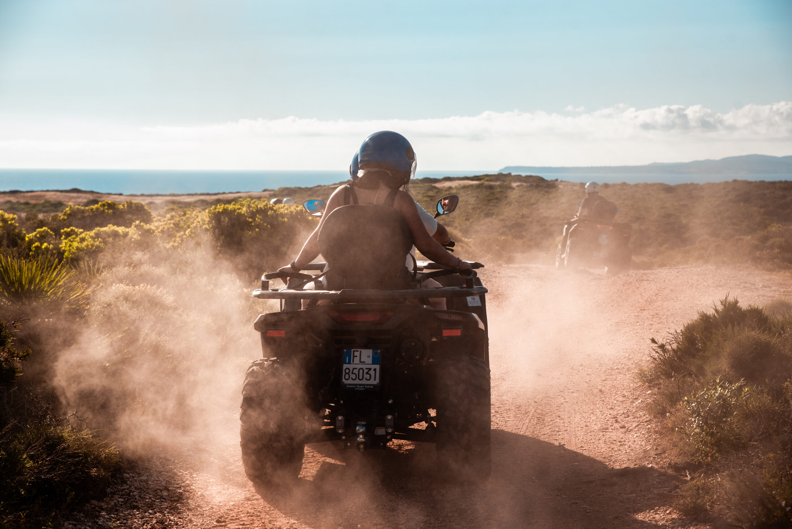 Quad con conductor y pasajero en una pista de tierra de Sant'Antioco, Cerdeña