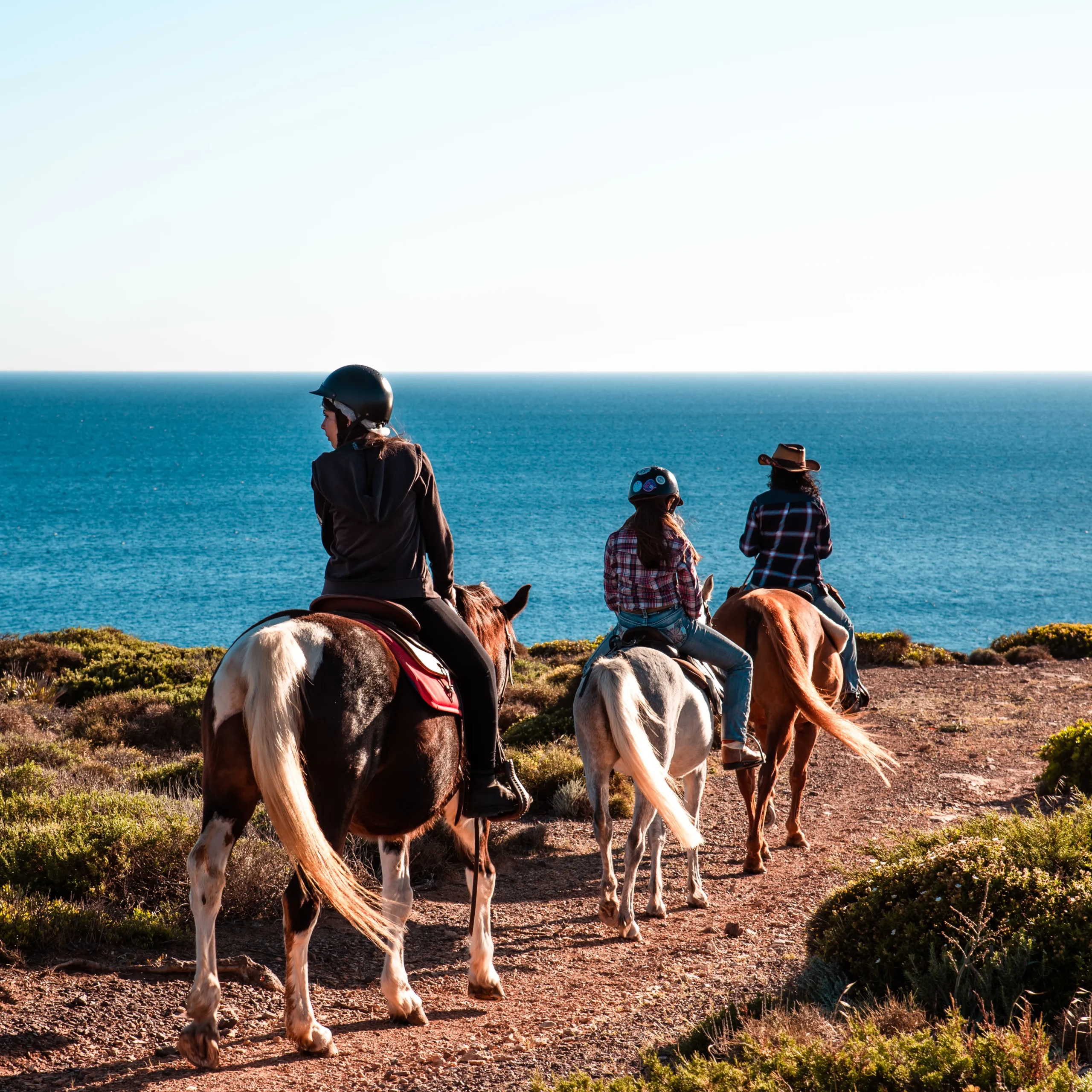 Jinetes con silla western por el sendero costero de Sant'Antioco, frente al mar de Cerdeña